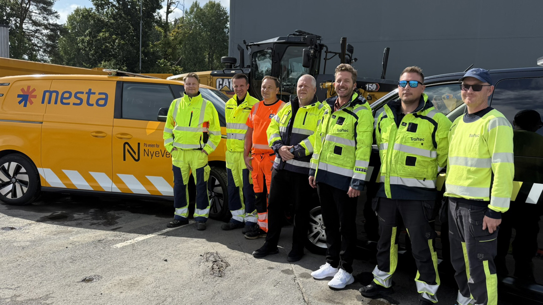Mestabil merket med teksten 'På veien for Nye Veier'. Syv menn i arbeidstøy fra Nye Veier, Mesta og Traftec.